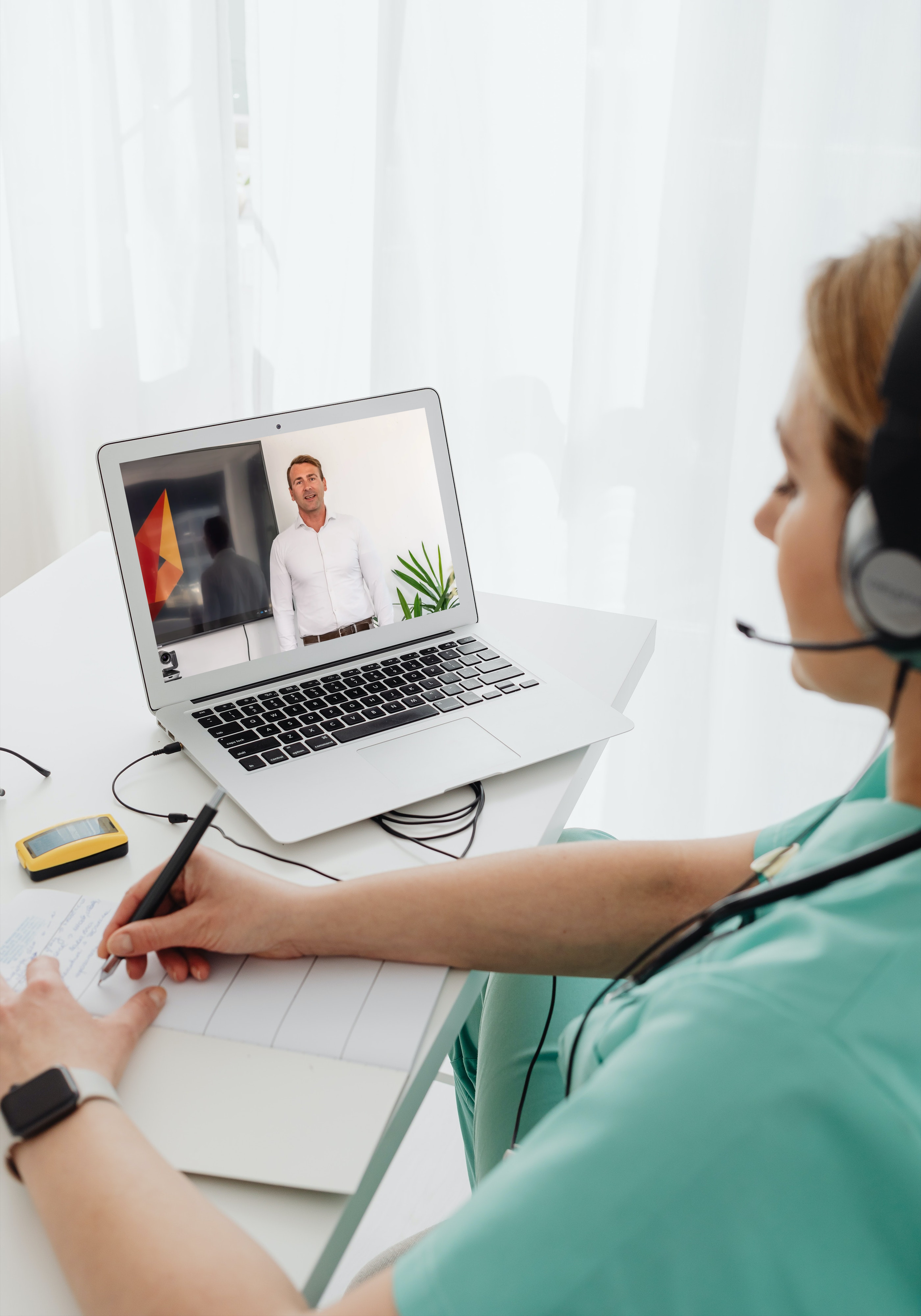 Frau sitzt im Homeoffice am Laptop und schaut sich eine Fortbildung von ringer Zeiterfassung an. Dabei macht sie sich Notizen zu den Lehrinhalten.